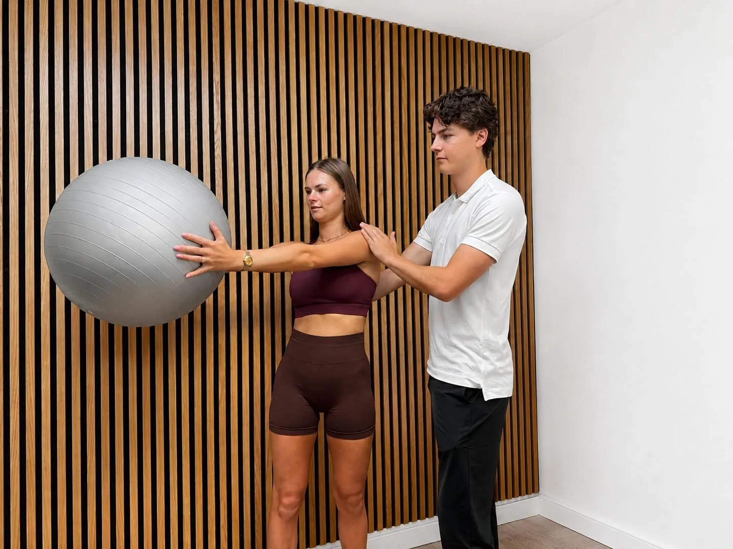 Will Sharman supporting a patient through a standing shoulder exercise.