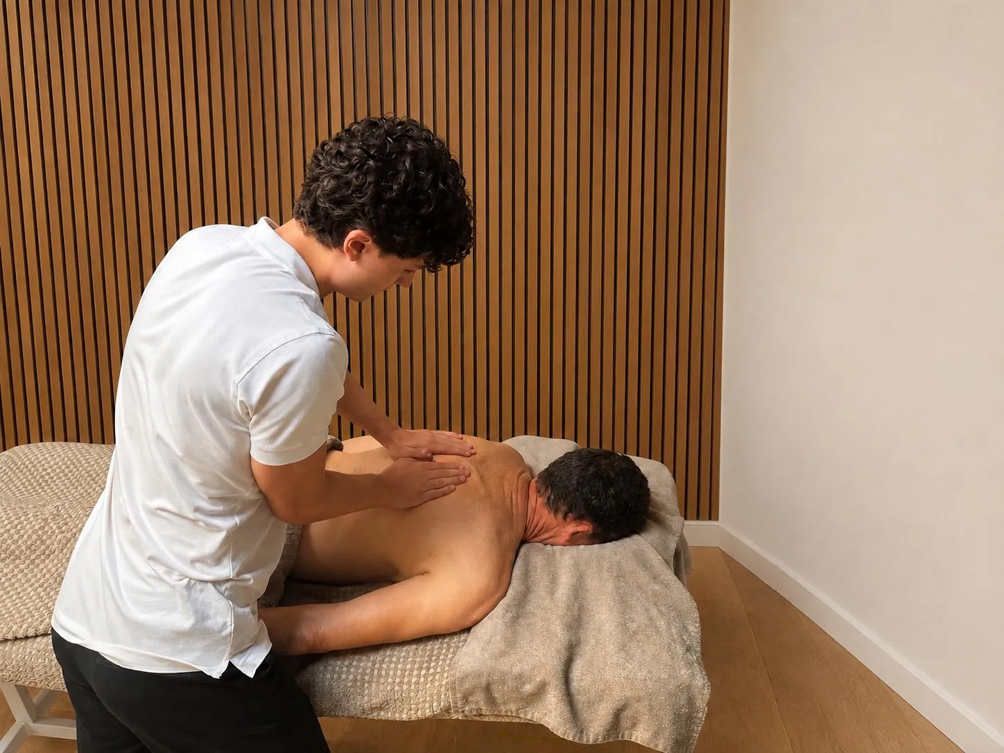 Will Sharman treating a patient's upper back on a massage couch.